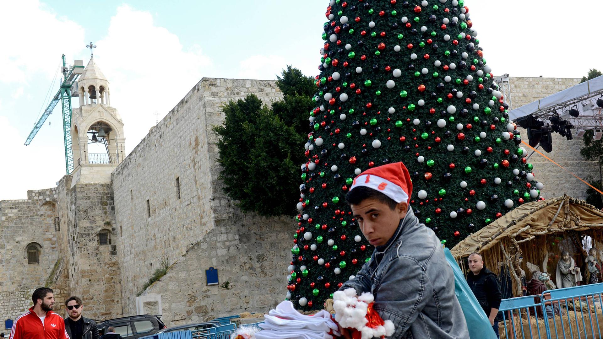 Ein palästinensischer Junge verkauft Weihnachtsmützen auf dem Manger Platz vor der Geburtskirche Jesu in Bethlehem. Ein palästinensischer Junge verkauft Weihnachtsmützen auf dem Manger Platz vor der Geburtskirche Jesu in Bethlehem.