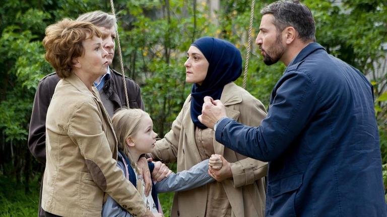 Großeltern (links) und Pflegeeltern (rechts) streiten um die kleine Pia. Die Großeltern wollen nicht, dass ihre Enkelin muslimisch aufwächst. Szenenfoto aus dem Spielfilm "Das deutsche Kind", ARD, 4. April 2018.