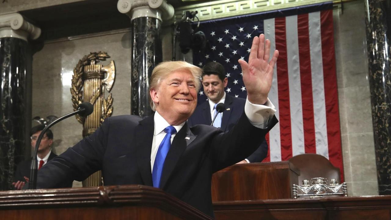 Trump winkt im Abgeordnetenhaus vom Rednerpult aus in den Saal. Trump winkt im Abgeordnetenhaus vom Rednerpult aus in den Saal.