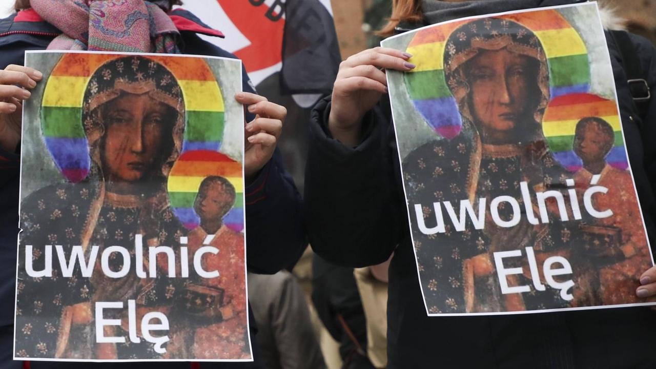 Zwei Plakate zeigen die Schwarze Madonna von Tschenstochau. Statt des goldenen Heiligenscheins trägt sie einen Heiligenschein in Regenbogenfarben. Zwei Plakate zeigen die Schwarze Madonna von Tschenstochau. Statt des goldenen Heiligenscheins trägt sie einen Heiligenschein in Regenbogenfarben.