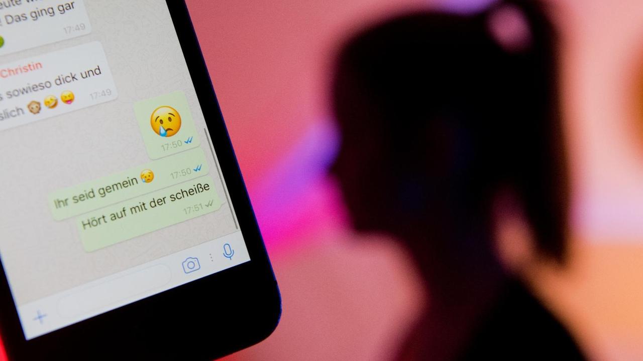 Ein junges Mädchen zeigt das Display eines Smartphones mit einem fiktiven Chatverlauf beim Messenger "WhatsApp". Ein junges Mädchen zeigt das Display eines Smartphones mit einem fiktiven Chatverlauf beim Messenger "WhatsApp".