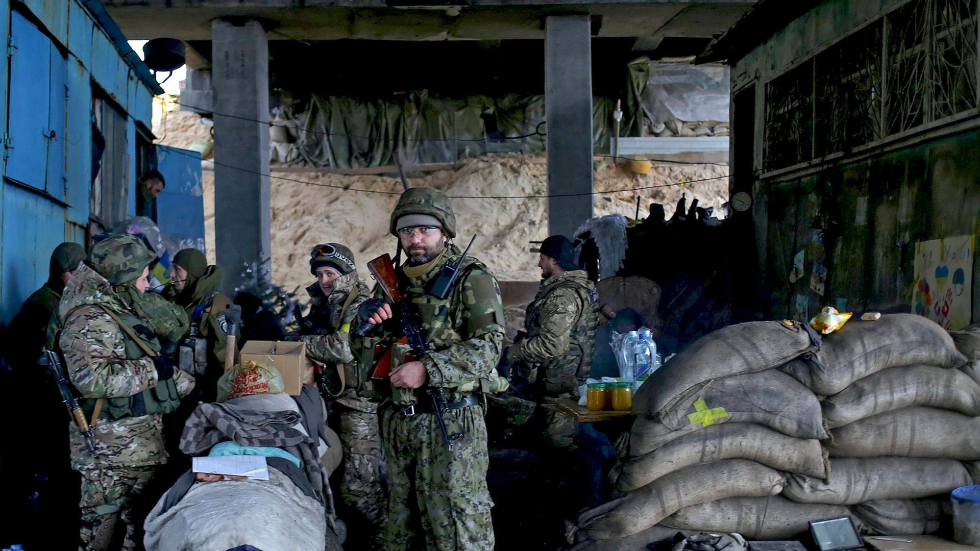Eine Gruppe von ukrainischen Soldaten steht bewaffnet und mit Sandsäcken gesichert unter einer Brücke. Eine Gruppe von ukrainischen Soldaten steht bewaffnet und mit Sandsäcken gesichert unter einer Brücke.
