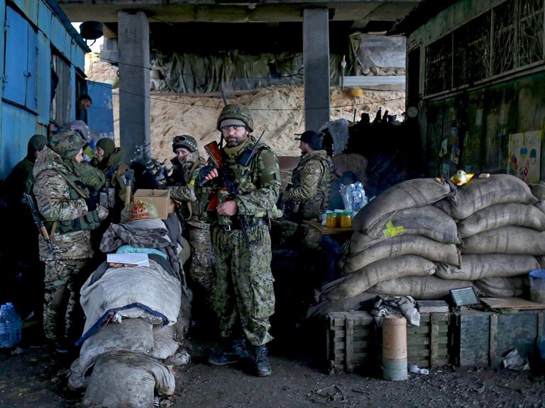 Eine Gruppe von ukrainischen Soldaten steht bewaffnet und mit Sandsäcken gesichert unter einer Brücke.