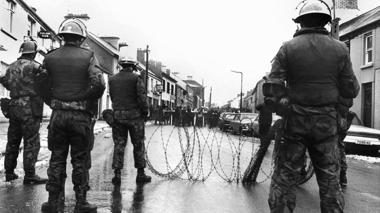 Britische Soldaten haben am 2. Februar 1972 in der nordirischen Stadt Dunsgiven mit Stacheldraht eine Straße vor nahenden Demonstranten gesperrt.