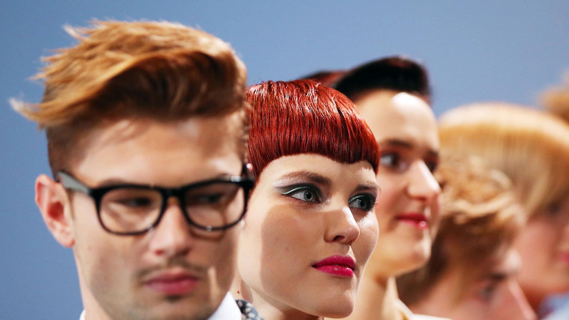 Models gehen mit neuen Frisuren über einen Laufsteg. Models gehen mit neuen Frisuren über einen Laufsteg.