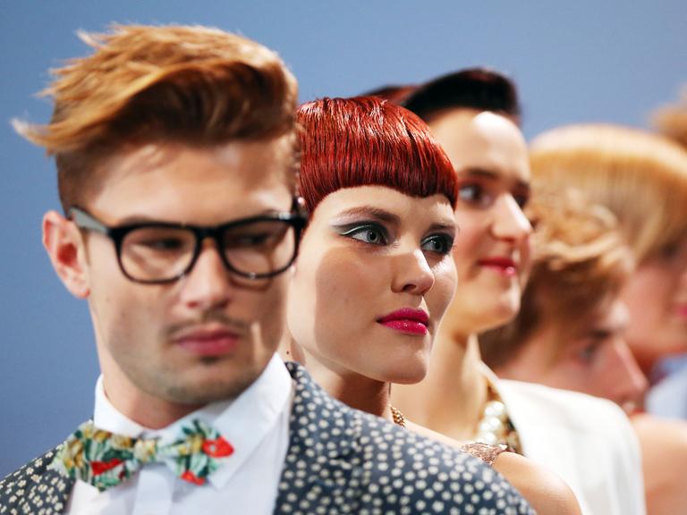 Models gehen mit neuen Frisuren über einen Laufsteg.