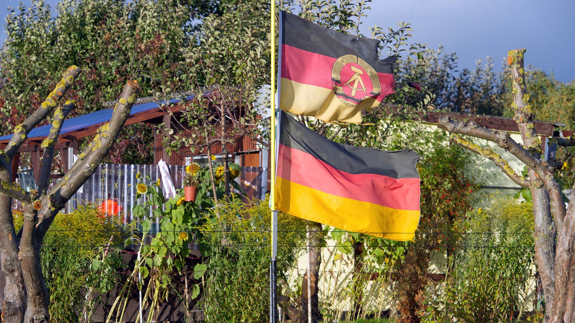 Eine DDR-Fahne und eine Deutschland-Flagge wehen an einem Fahnenmast in der Kleingartenanlage "Samtenser Frühling" in Samtens auf der Ostseeinsel Rügen. Eine DDR-Fahne und eine Deutschland-Flagge wehen an einem Fahnenmast in der Kleingartenanlage "Samtenser Frühling" in Samtens auf der Ostseeinsel Rügen.