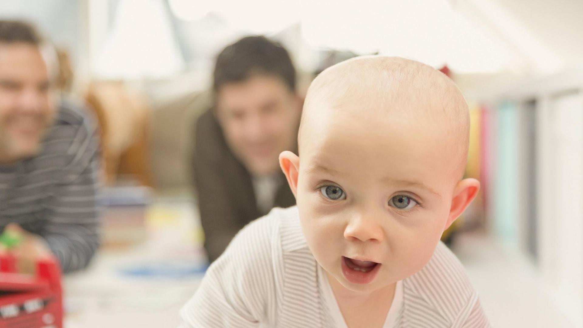Zwei Väter mit Baby, das im Vordergrund zu sehen ist Zwei Väter mit Baby, das im Vordergrund zu sehen ist