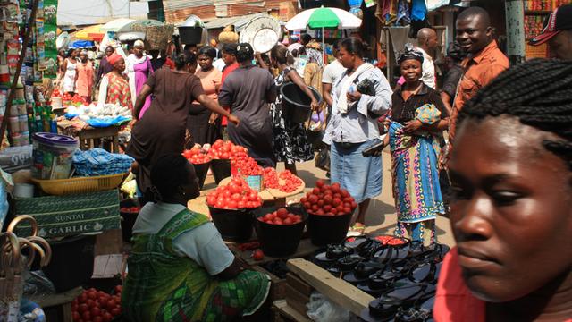 Menschen auf Markt in Afrika stehen vor Stand.
