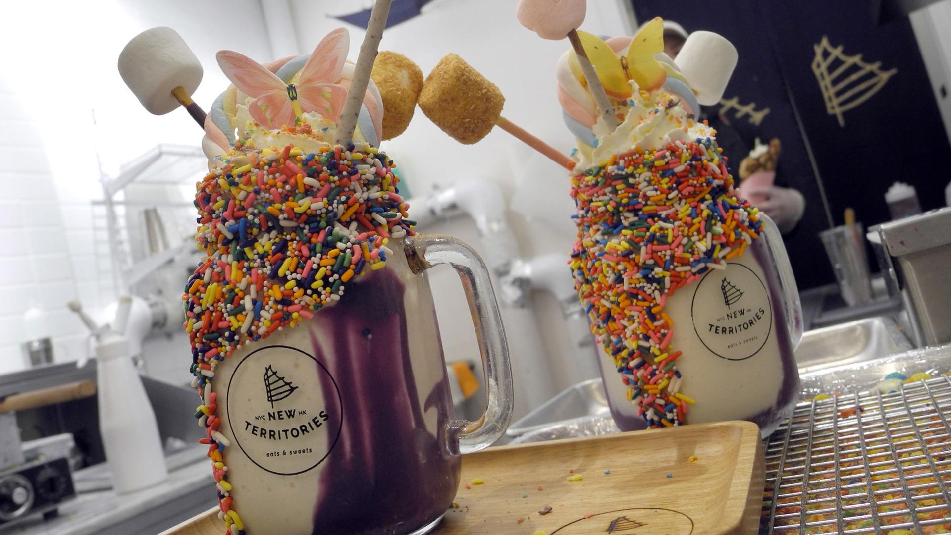 Zwei Milchshakes namens "Unicorn Parade" in einem Cafe in New York. Für die Einhorn-Optik sorgen bunte Streusel am Glasrand und eine lilafarbene, als Ube bekannte Paste aus pürierten Süßkartoffeln. Verziert wird das Getränk mit einer regenbogenfarbenen Marshmallow-Stange und dünnen Keks-Stäbchen Zwei Milchshakes namens "Unicorn Parade" in einem Cafe in New York. Für die Einhorn-Optik sorgen bunte Streusel am Glasrand und eine lilafarbene, als Ube bekannte Paste aus pürierten Süßkartoffeln. Verziert wird das Getränk mit einer regenbogenfarbenen Marshmallow-Stange und dünnen Keks-Stäbchen