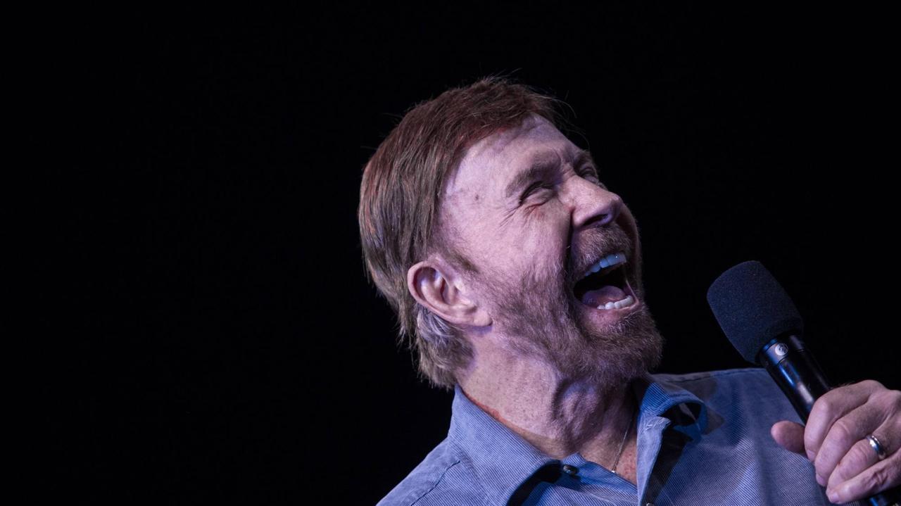 Porträtaufnahme von Chuck Norris aus dem Jahr 2018, mit kurzem Haar und Bart. Er hält ein Mikrofon in der Hand. Porträtaufnahme von Chuck Norris aus dem Jahr 2018, mit kurzem Haar und Bart. Er hält ein Mikrofon in der Hand.