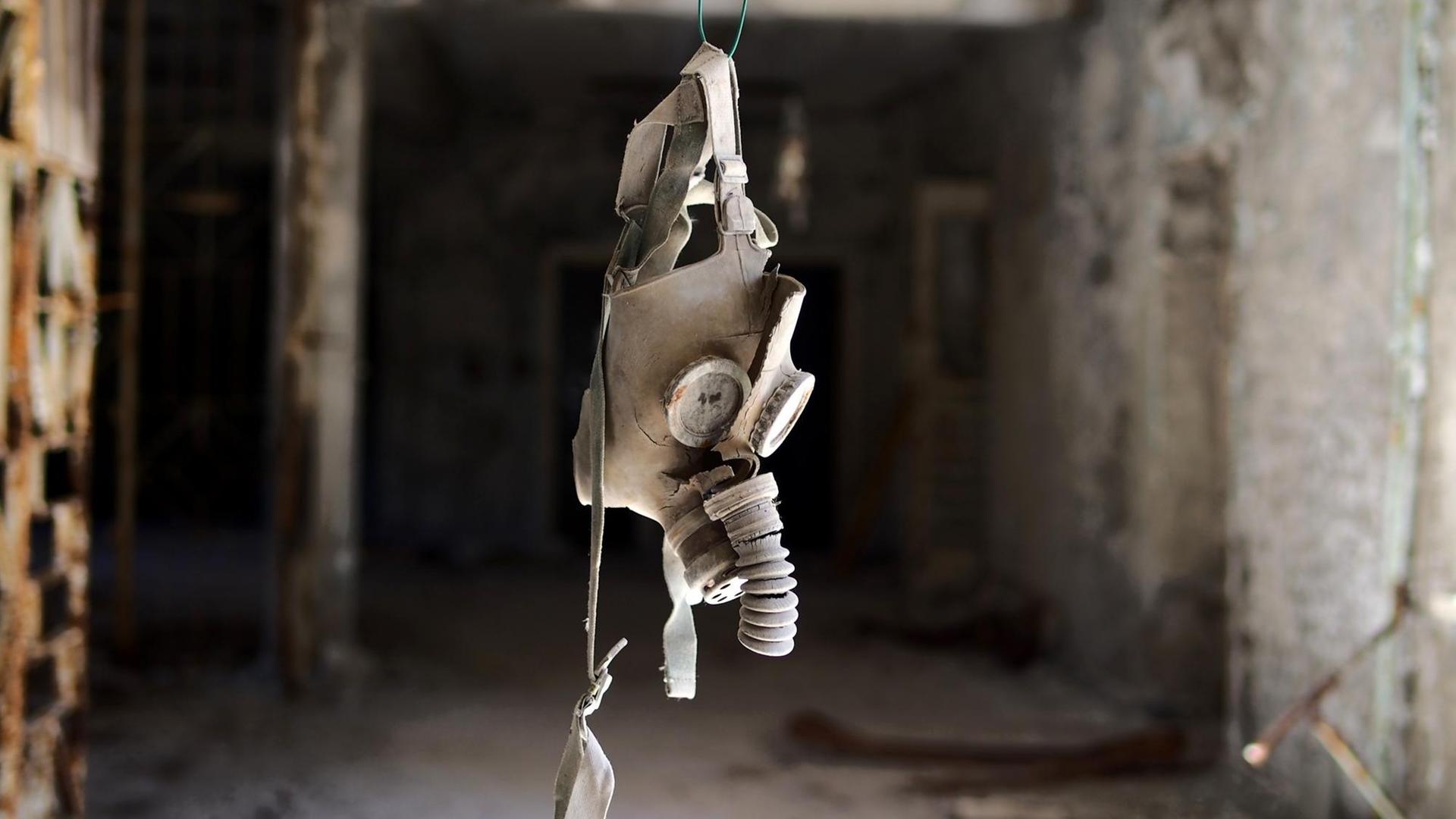 Eine Gasmaske hängt in einem Gang eines zerstörten Gebäudes von der Decke. Eine Gasmaske hängt in einem Gang eines zerstörten Gebäudes von der Decke.