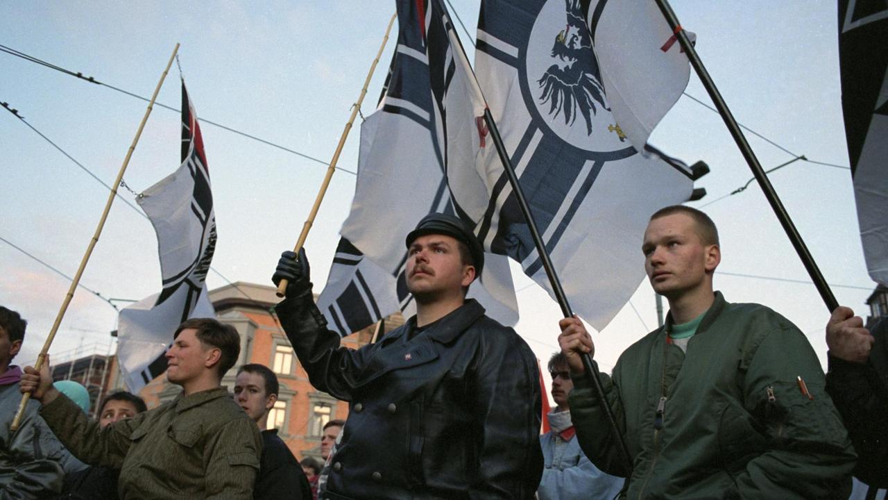 Neonazis stehen mit Reichskriegsflaggen in der Hand zusammen. Ihr Blick ist ernst und entschlossen. Neonazis stehen mit Reichskriegsflaggen in der Hand zusammen. Ihr Blick ist ernst und entschlossen.