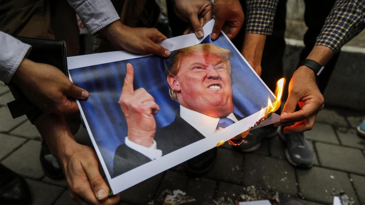 Menschen im Iran verbrennen ein Bild von US-Präsident Donald Trump, nachdem dieser angekündigt hat, nicht mehr am Atomabkommen festzuhalten. Menschen im Iran verbrennen ein Bild von US-Präsident Donald Trump, nachdem dieser angekündigt hat, nicht mehr am Atomabkommen festzuhalten.