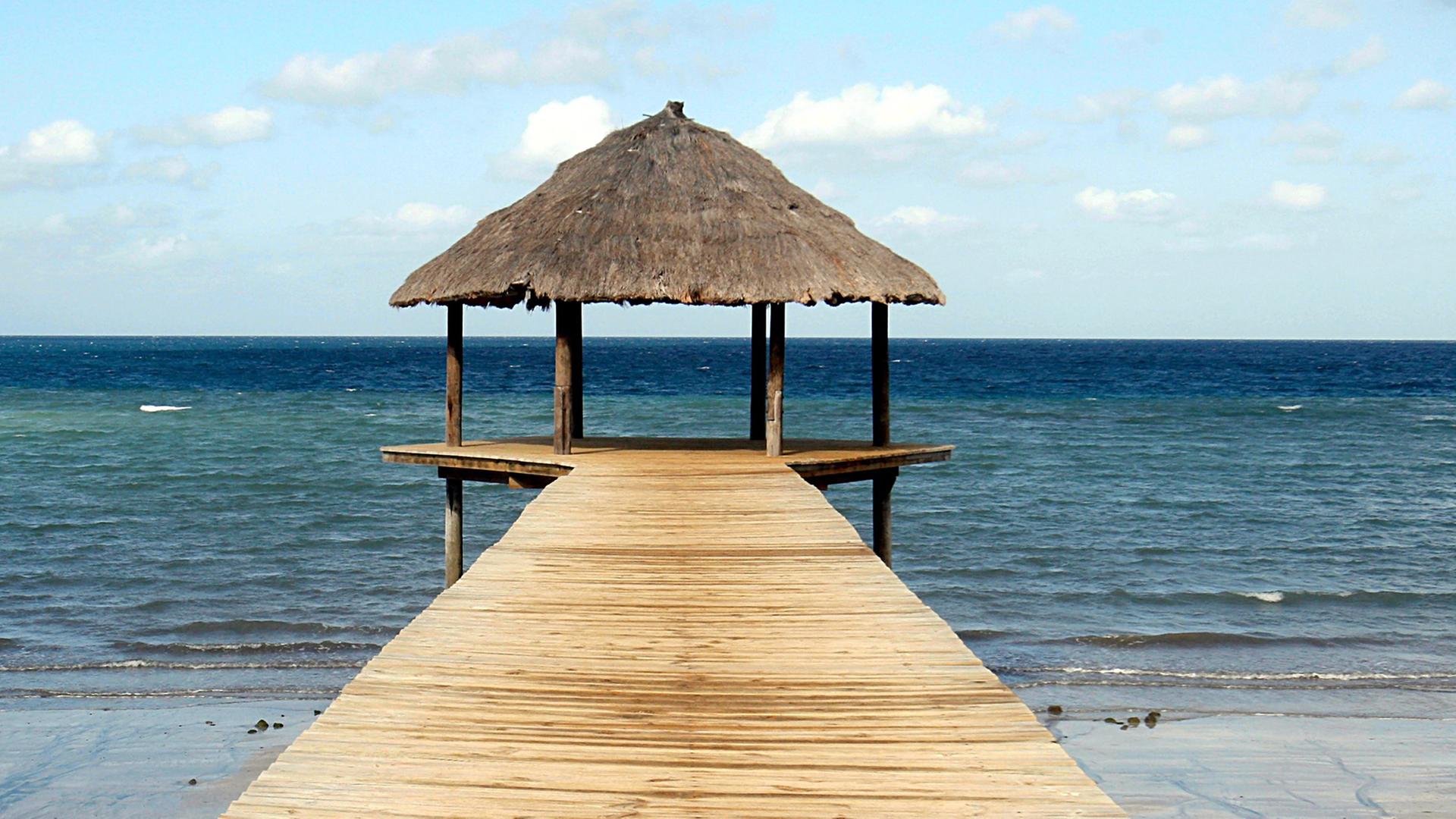 Ein Holzsteg, am Ende mit einer kleinen Hütte, führt aufs Meer Ein Holzsteg, am Ende mit einer kleinen Hütte, führt aufs Meer