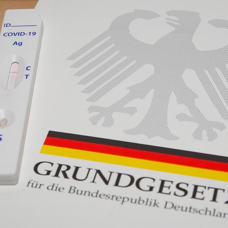 Ein negativer Corona-Schnelltest liegt auf dem Grundgesetz für die Bundesrepublik Deutschland