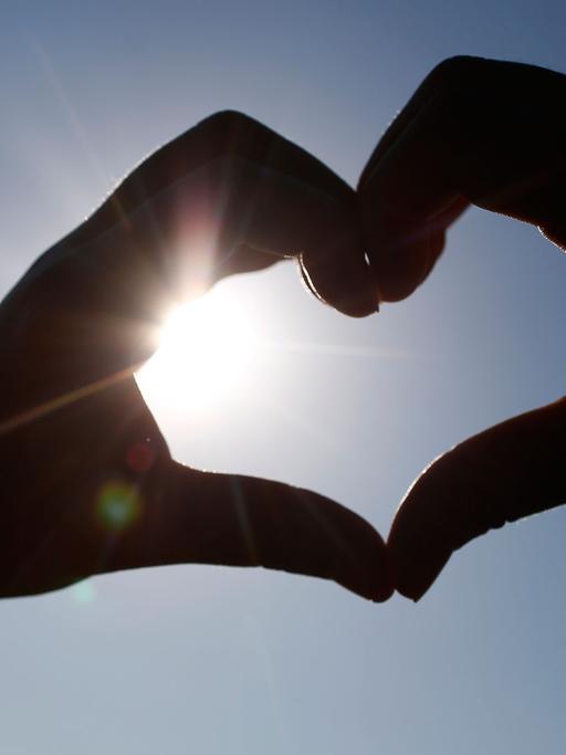 Ein vor der Sonne mit Händen geformtes Herz ist am 02.07.2015 in Dortmund zu sehen.