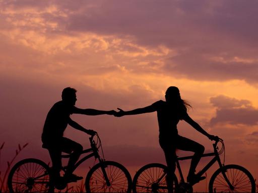 Ein Paar fährt bei Sonnenuntergang auf dem Fahrrad.