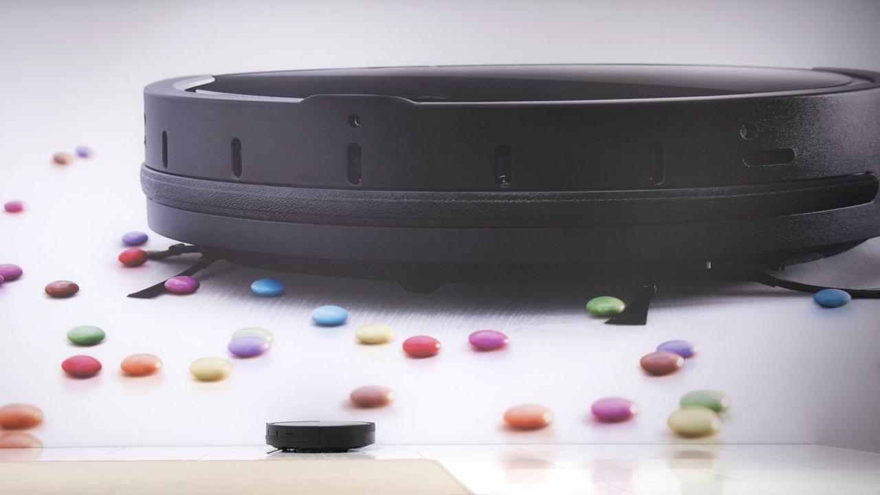Prototyp eines Staubsaugeroboters sammelt kleine bunte Schokobonbons ein. Prototyp eines Staubsaugeroboters sammelt kleine bunte Schokobonbons ein.