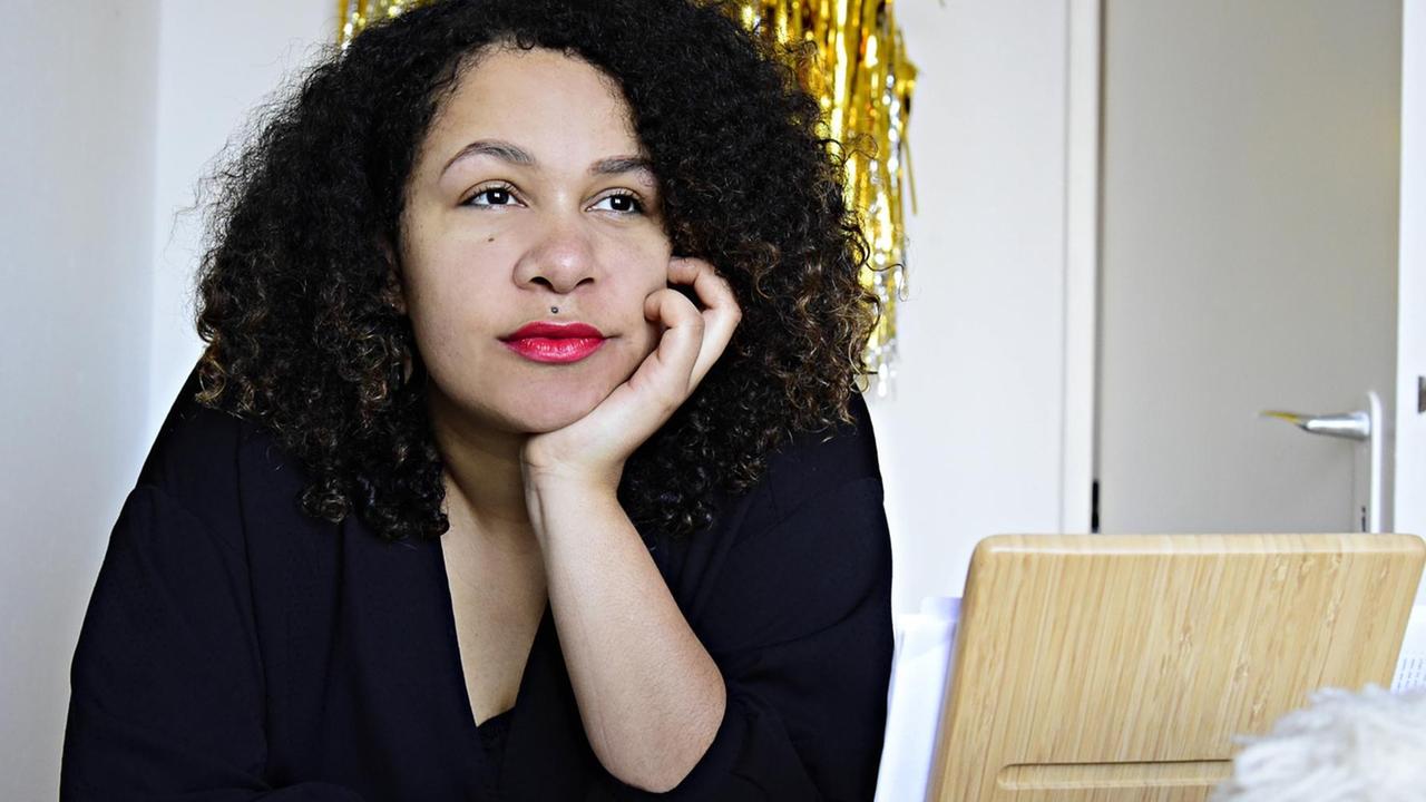 Olivia Wenzel lehnt auf ihrem Schreibtisch und blickt nachdenklich ins Off. Olivia Wenzel lehnt auf ihrem Schreibtisch und blickt nachdenklich ins Off.