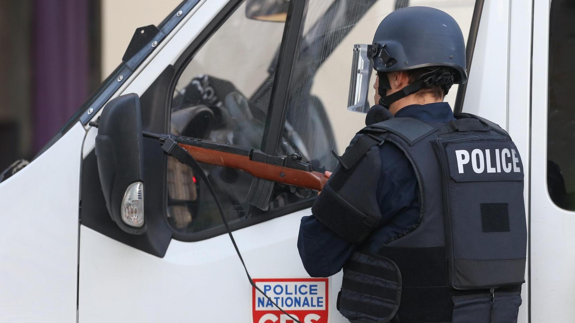 Ein Polizist mit Sicherheitsweste steht vor einem Polizeiauto.