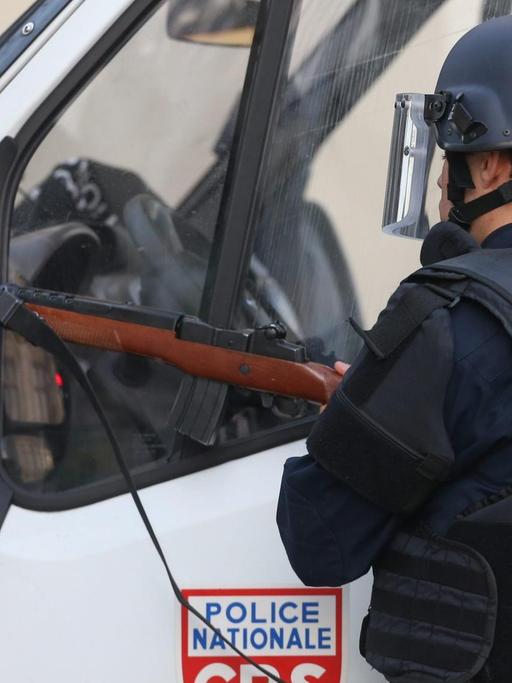 Ein Polizist mit Sicherheitsweste steht vor einem Polizeiauto.
