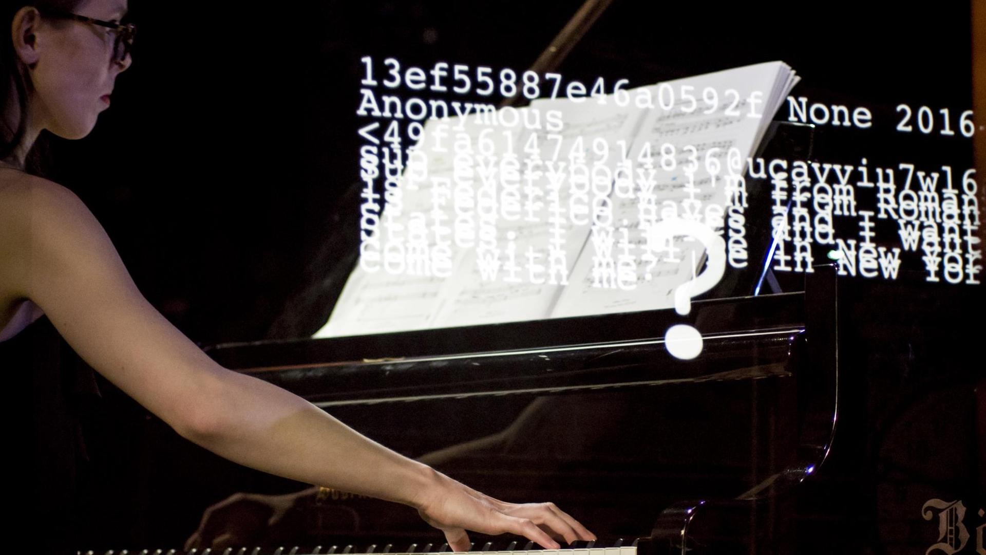 Eine Pianistin spielt am Flügel, während Zifferncodes und Wörter auf die Szene proojiziert werden Eine Pianistin spielt am Flügel, während Zifferncodes und Wörter auf die Szene proojiziert werden