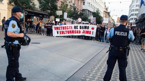 Demonstranten in der slowenischen Hauptstadt Ljubljana protestieren gegen die Kulturpolitik der Regierung. Zwei Polizisten beobachten die Szenerie.