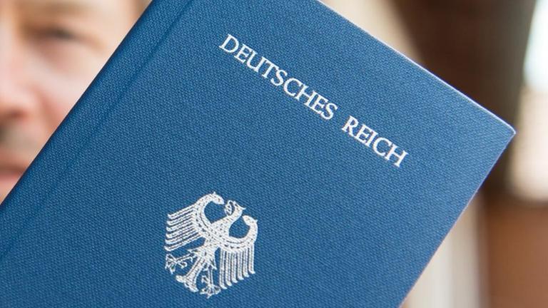 Ein "Reichsbürger" posiert mit seinem "Deutsches Reich Reisepass".
