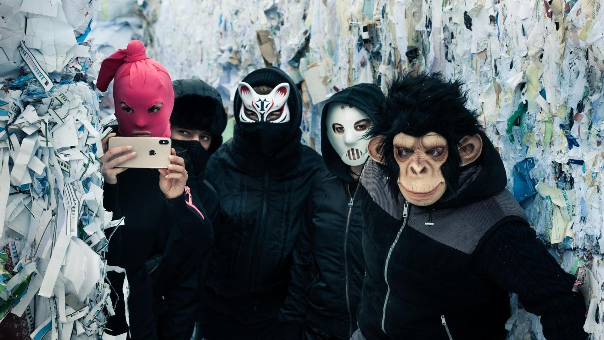 Fünf Jugendliche in dunklen Klamotten und mit Masken vor den Gesichtern. Fünf Jugendliche in dunklen Klamotten und mit Masken vor den Gesichtern.