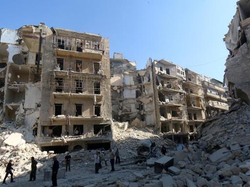Menschen stehen vor zerstörten Häusern in der syrischen Stadt Aleppo