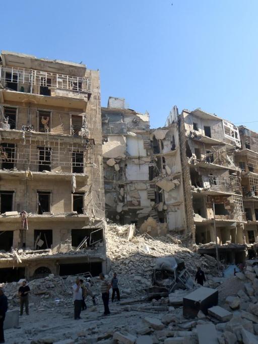 Menschen stehen vor zerstörten Häusern in der syrischen Stadt Aleppo