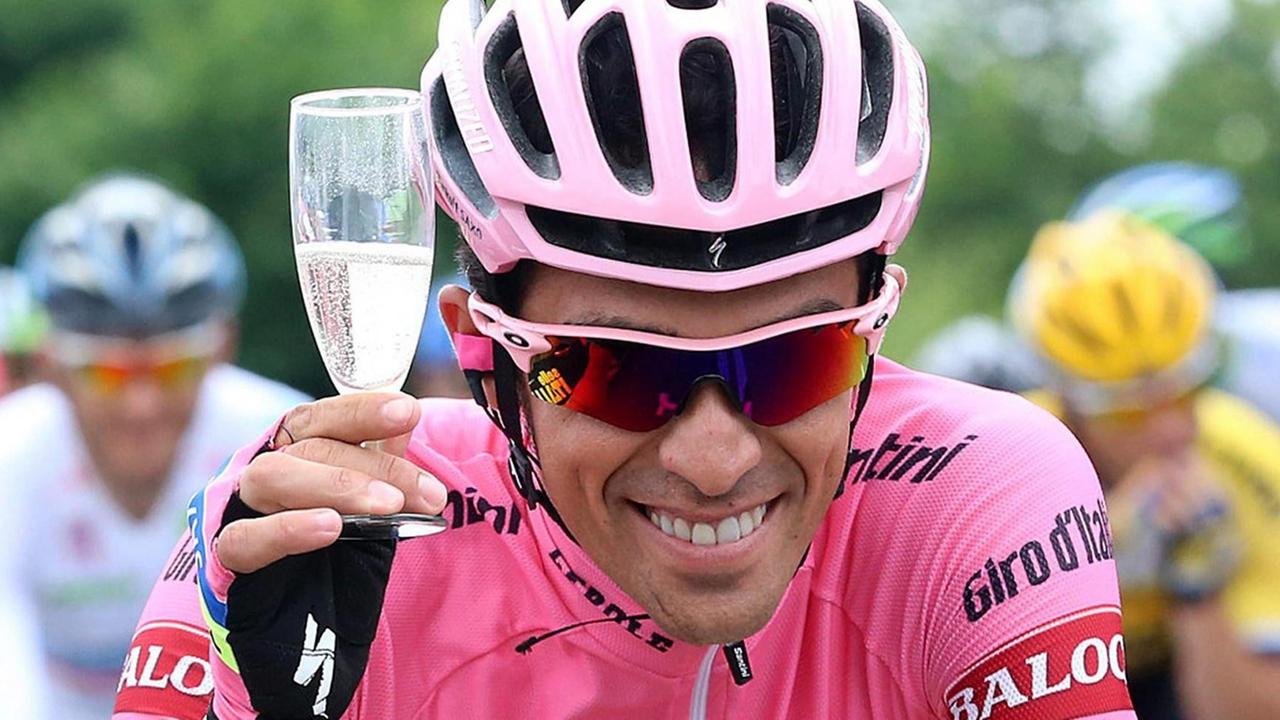 Alberto Contador auf seinem Rad, in der Hand ein Sektglas.