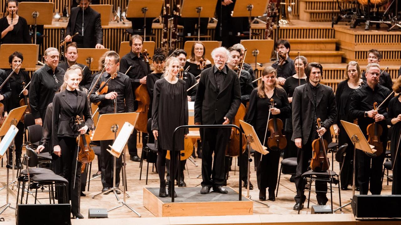 Komponistin und Dirigent stehen vor dem Orchester. Komponistin und Dirigent stehen vor dem Orchester.