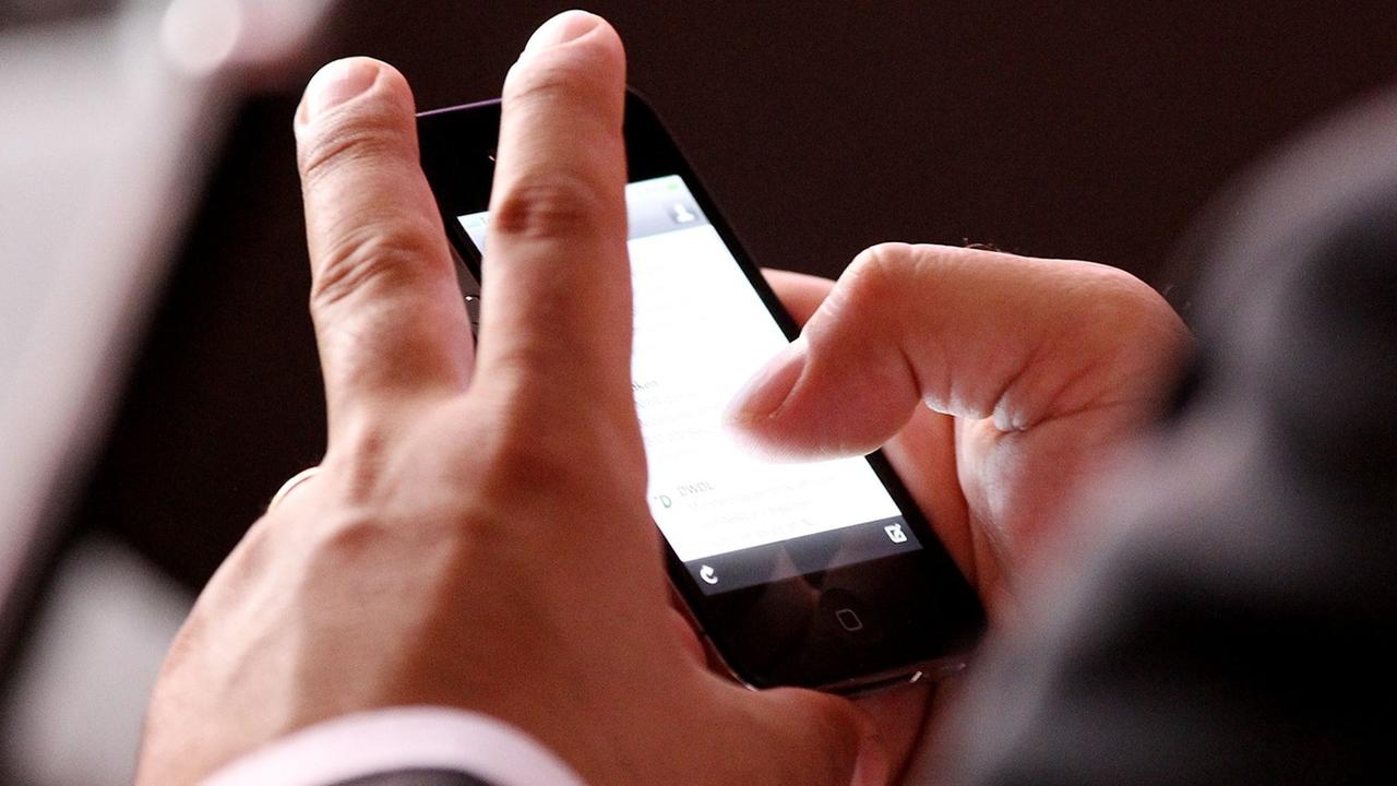 Ein Mann schaut auf das Display eines Smartphones. Ein Mann schaut auf das Display eines Smartphones.