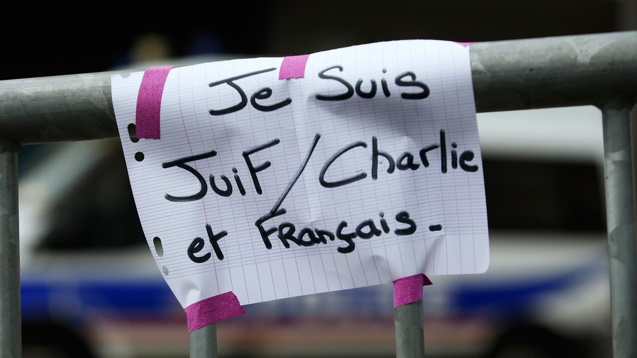 Ein Schild mit der Aufschrift "Je suis Juif, Charlie et Francais" - "Ich bin Jude, Charlie und Franzose" auf einer Sicherheitsabsperrung am 10.1.2014, einen Tag, nachdem vier Juden in einem koscheren Supermarkt von Paris ermordet wurden.