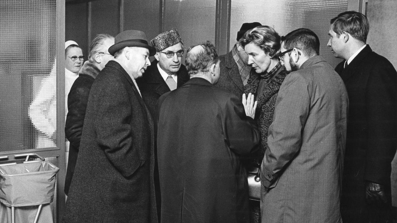 In dunklen Mänteln steht eine Gruppe von WHO-Vertretern 1970 vor der Zentralen Pockenbehandlungsstelle in Wimbern.