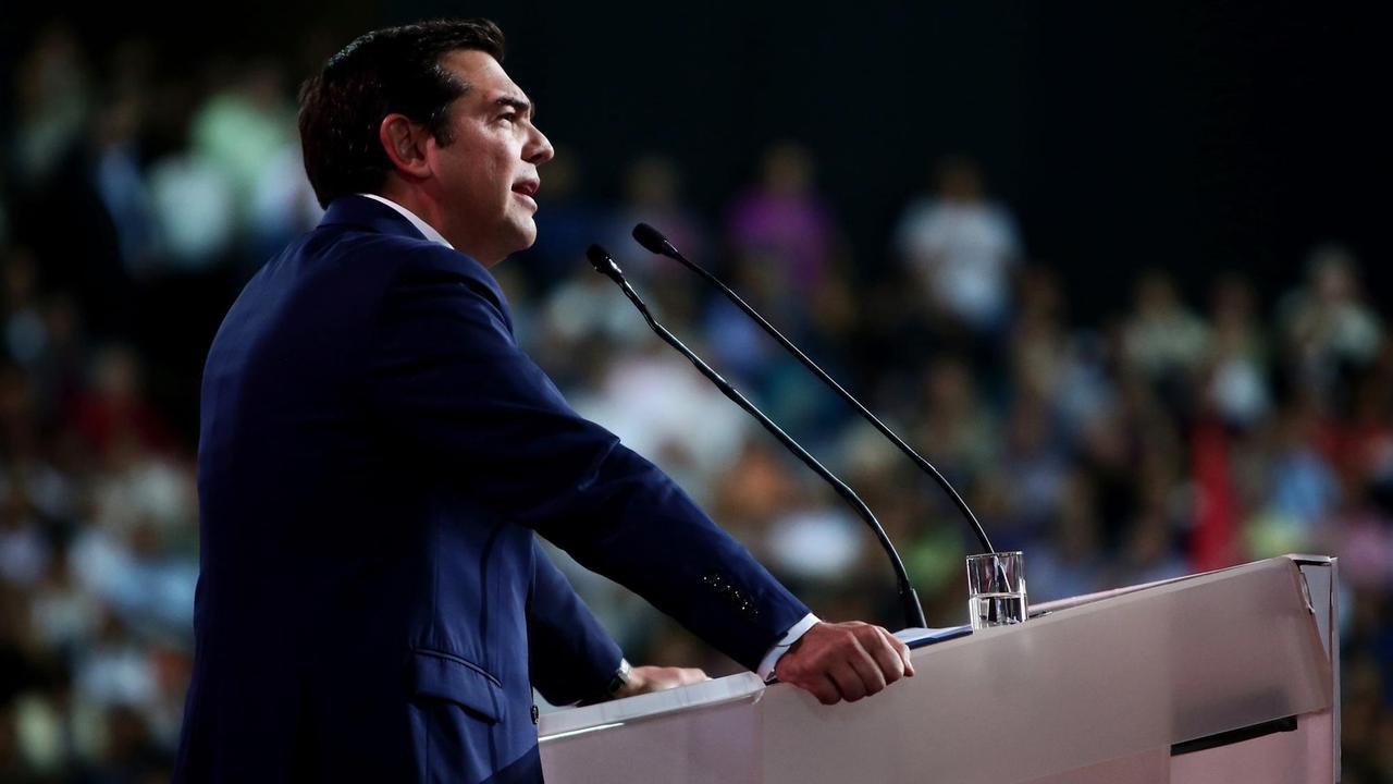 Das Bild zeigt den griechischen Ministerpräsidenten und Chef der regierenden Syriza-Partei, Alexis Tsipras, während einer Rede auf dem Parteitag in Athen. Zu sehen ist er von der Seite, im Hintergrund sind verschwommen zahlreiche Delegierte im Saal zu sehen.