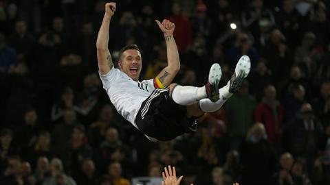 Lukas Podolski wird nach seinem letzten Länderspiel von seinen Mannschaftskollegen in die Luft geworfen.