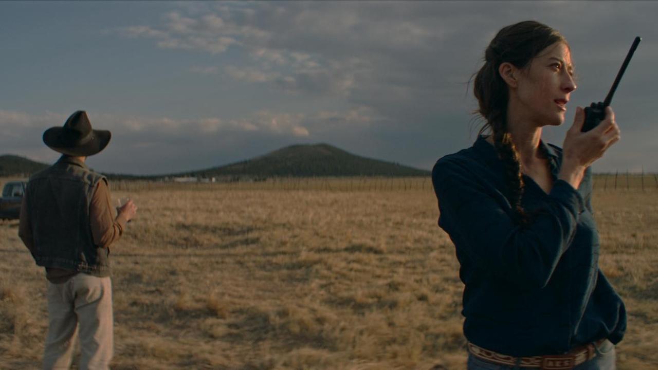 Eine Szene aus Carlos Reygadas' Film "Nuestro Tiempo": Eine Frau steht mit einem Walkie Talkie vor einer Prärie-Landschaft, hinter ihr steht ein Mann, der von ihr abgewendet ist und in die Ferne schaut