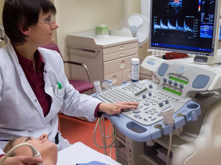 Ultraschall-Untersuchung der Schilddrüse im Krankenhaus, Ärztin mit Patientin.