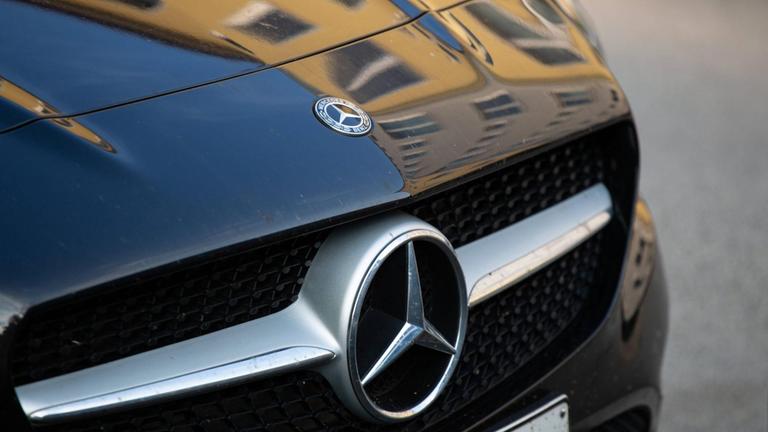 Die Front eines schwarzen Mercedes mit dem bekannten Stern auf der Kühlerhaube.
