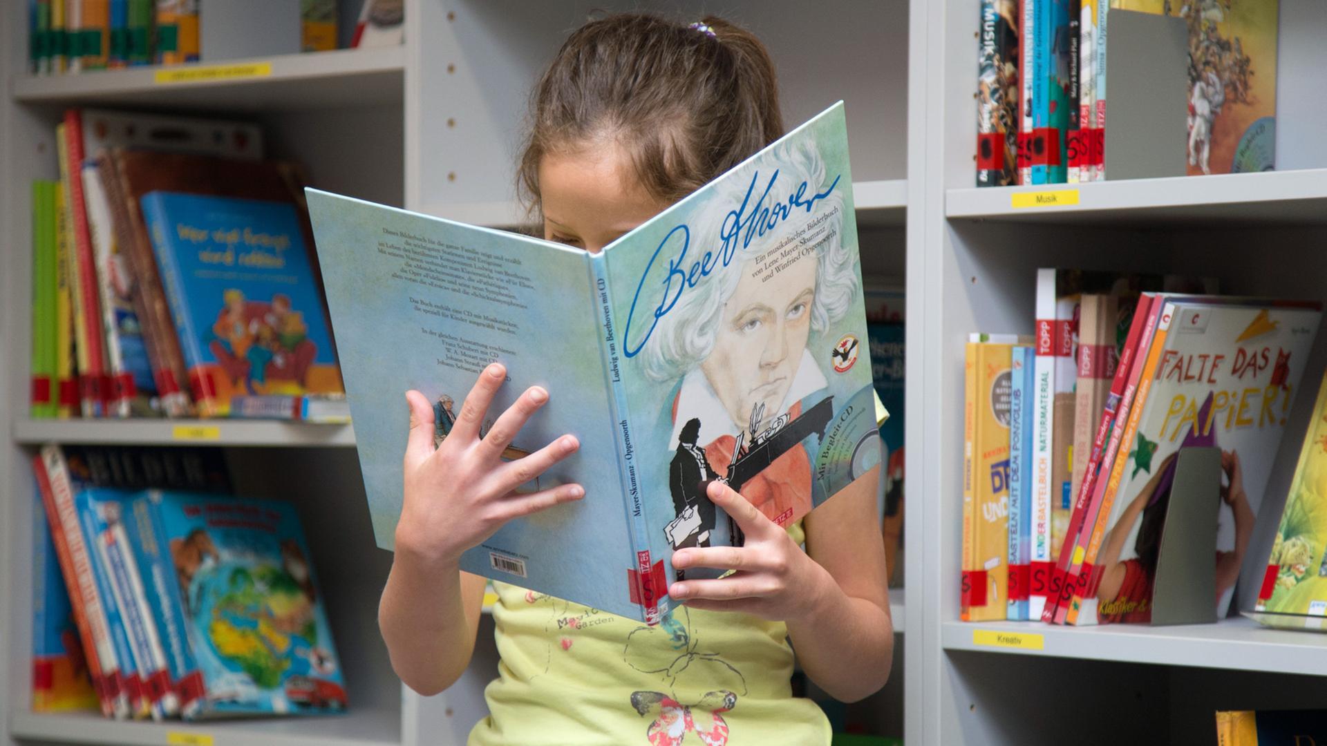 Eine Schülerin blickt in der Bibliothek der Grundschule auf dem Süsteresch in Schüttorf / Niedersachsen in ein Sachbuch über "Beethoven". Die Schule ist Hauptpreisträger beim Deutschen Schulpreis 2016. Eine Schülerin blickt in der Bibliothek der Grundschule auf dem Süsteresch in Schüttorf / Niedersachsen in ein Sachbuch über "Beethoven". Die Schule ist Hauptpreisträger beim Deutschen Schulpreis 2016.