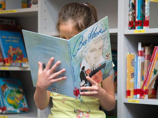 Eine Schülerin blickt in der Bibliothek der Grundschule auf dem Süsteresch in Schüttorf / Niedersachsen in ein Sachbuch über "Beethoven". Die Schule ist Hauptpreisträger beim Deutschen Schulpreis 2016.