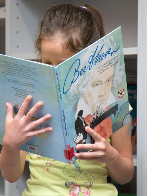 Eine Schülerin blickt in der Bibliothek der Grundschule auf dem Süsteresch in Schüttorf / Niedersachsen in ein Sachbuch über "Beethoven". Die Schule ist Hauptpreisträger beim Deutschen Schulpreis 2016.