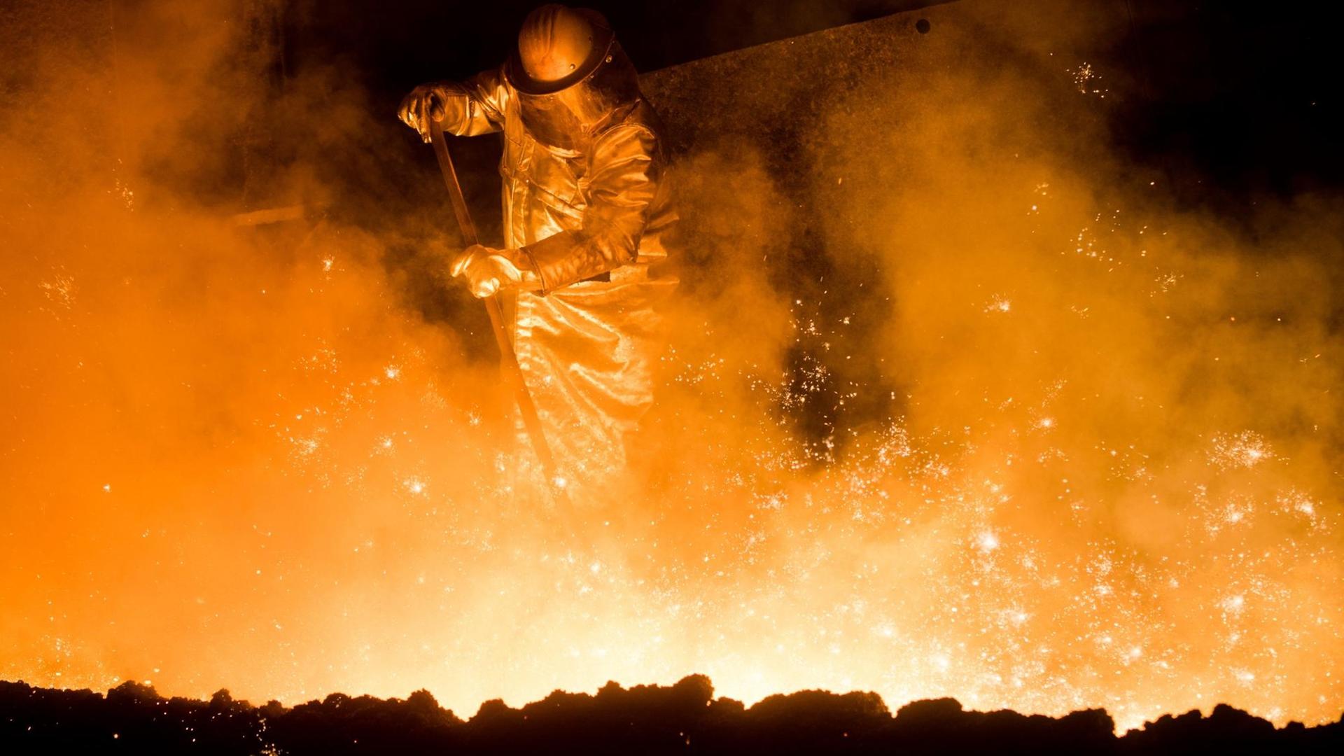 Ein Mitarbeiter in Schutzkleidung arbeitet am in Salzgitter auf dem Gelände der Salzgitter AG vor einem angestochenen Hochofen. Ein Mitarbeiter in Schutzkleidung arbeitet am in Salzgitter auf dem Gelände der Salzgitter AG vor einem angestochenen Hochofen.