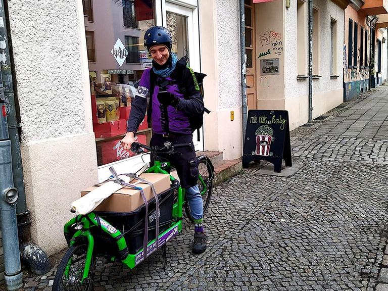 Fahrradkurier Simon Richter steht mit seinem Lastenrad auf einem Bürgersteig in Berlin.