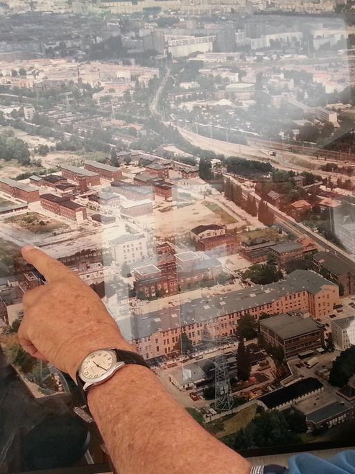 Horst Spörck vor einer Luftbildaufnahme von Rummelsburg – zu sehen die ehemalige Haftanstalt Rummelsburg, worauf er zeigt. Er war als Kind in den 30er und 40er Jahren im Großen Friedrichs-Waisenhaus in Rummelsburg.