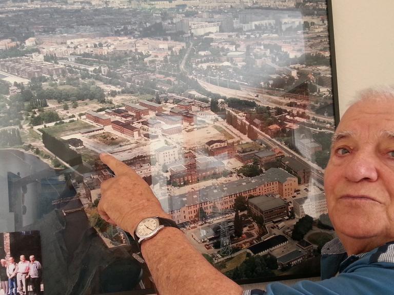 Horst Spörck vor einer Luftbildaufnahme von Rummelsburg – zu sehen die ehemalige Haftanstalt Rummelsburg, worauf er zeigt. Er war als Kind in den 30er und 40er Jahren im Großen Friedrichs-Waisenhaus in Rummelsburg.