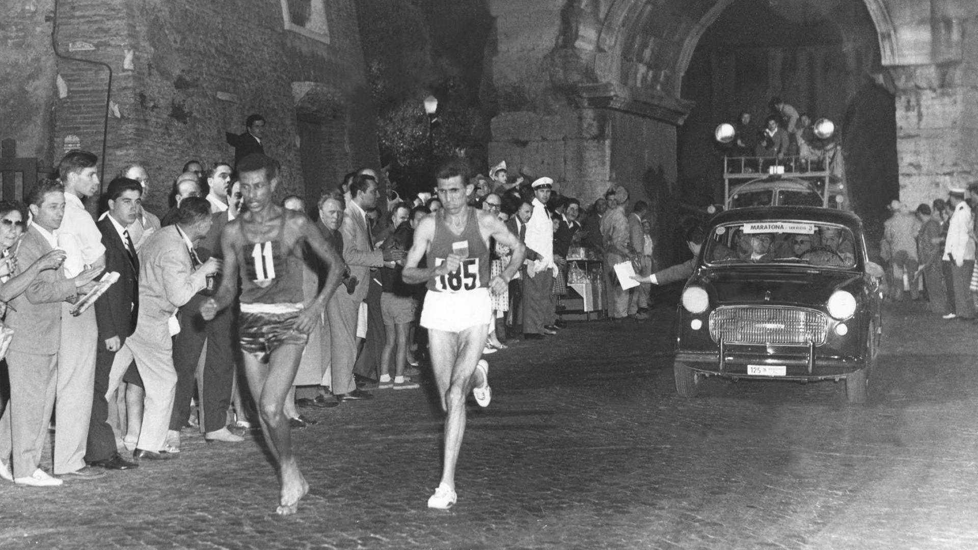 Gemeinsam mit dem späteren Zweitplatzierten Rhadi Ben Abdesselam (Marokko) passiert der 28-jährige Leibgardist von Kaiser Haile Selassie, Abebe Bikila, beim olympischen Marathonlauf in Rom die Porta San Sebastiano. Gemeinsam mit dem späteren Zweitplatzierten Rhadi Ben Abdesselam (Marokko) passiert der 28-jährige Leibgardist von Kaiser Haile Selassie, Abebe Bikila, beim olympischen Marathonlauf in Rom die Porta San Sebastiano.